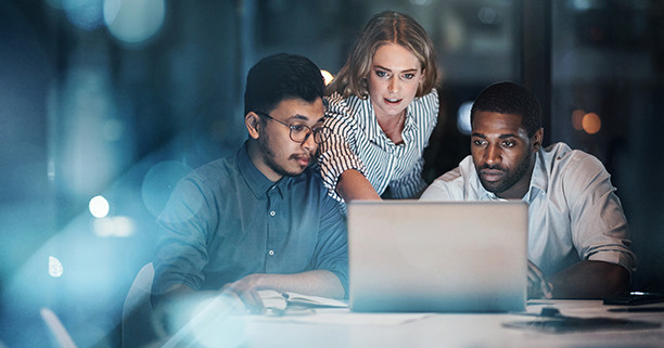 Cropped shot of three young business people working together on a laptop in their office late at night